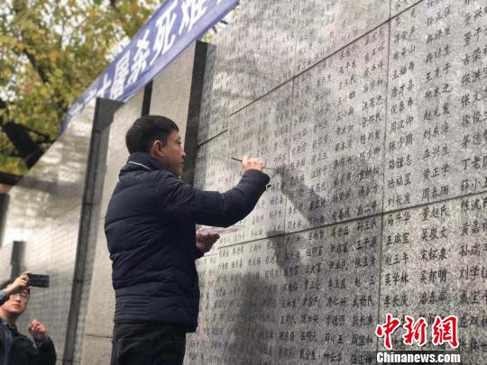 10日晨，下著小雨。南京大屠殺幸存者、死難者遺屬、學(xué)生們依次描寫名字，祭悼南京大屠殺遇難同胞。淡淡的墨汁摻著雨水，滲入了刻在紀(jì)念館灰色厚重石壁上的黑色名字中?！≈鞎苑f 攝
